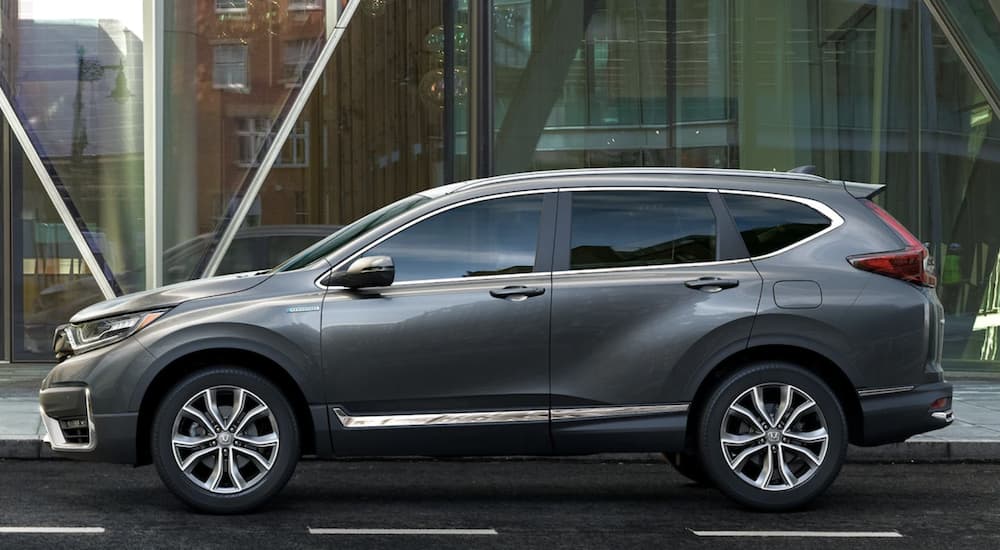 A grey 2022 Honda CR-V Hybrid Touring is shown from the side parked in front of a city building.