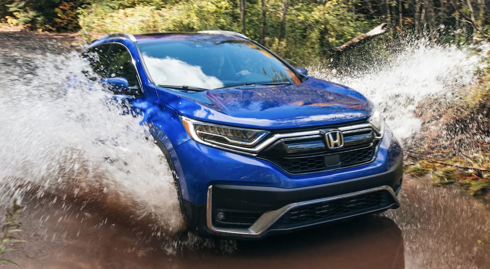 A blue 2022 Honda CR-V Touring is shown from the front off-roading through a river.