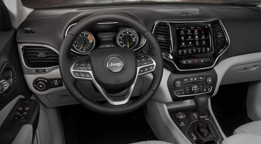 The black interior of a 2022 Jeep Cherokee shows the steering wheel and infotainment screen.