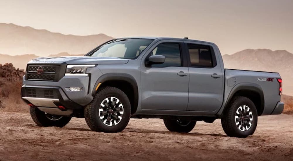 A grey 2022 Nissan Frontier is shown from the side while parked off-road.