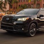 A black 2022 Subaru Ascent is shown driving on a city street.