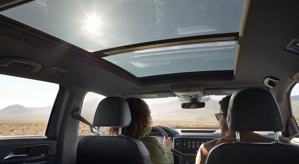 A couple is shown driving a 2022 Volkswagen Atlas Cross Sport.