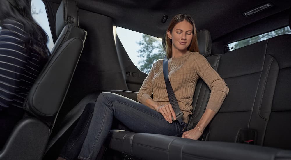 A person is shown buckling into the back seat of a 2023 Chevy Tahoe.