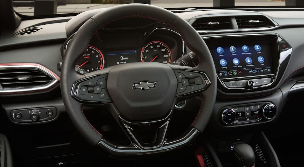 The black interior of a 2023 Chevy Trailblazer shows the steering wheel and infotainment screen.