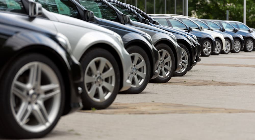 A line of cars is shown on a dealership lot.