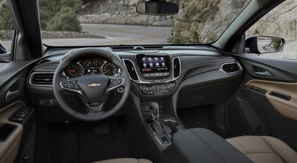 The black interior of a 2022 Chevy Equinox shows the steering wheel and infotainment screen.