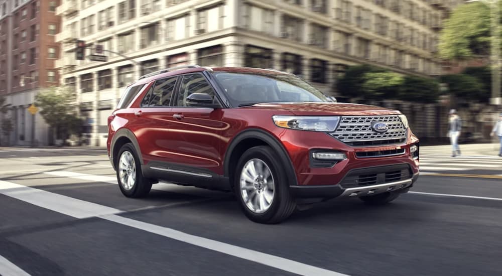 A red 2022 Ford Explorer is shown from the front driving through a city.