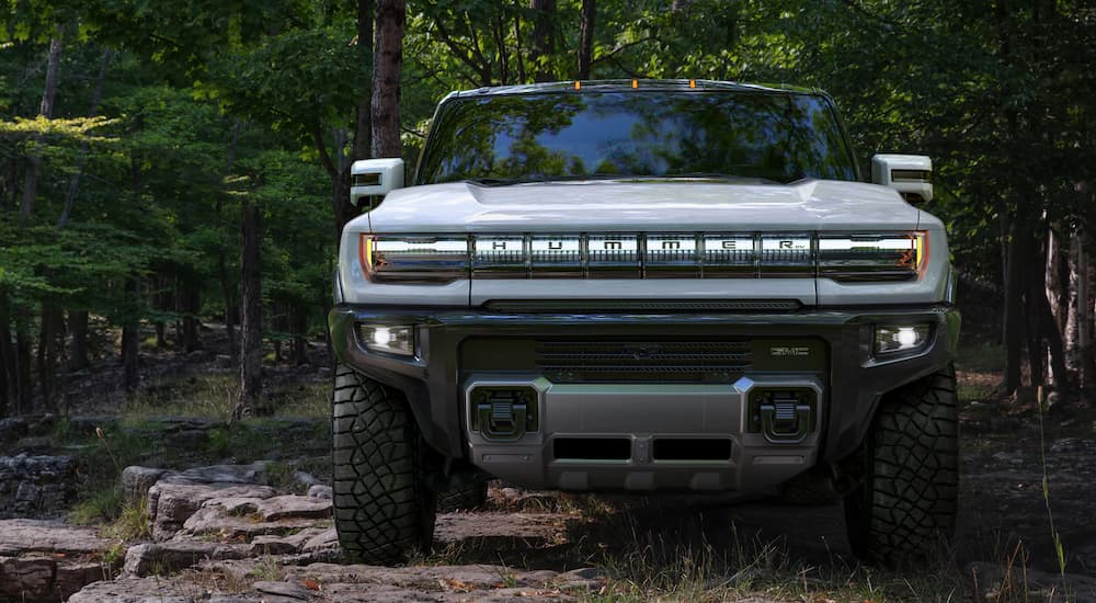 A white 2022 Hummer EV is shown from the front on a forest path.