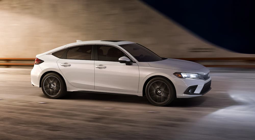 A white 2022 Honda Civic Hatchback is shown from the side after leaving a Honda dealership.