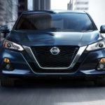 A pale blue 2022 Nissan Altima is shown from the front while driving during a 2022 Nissan Altima vs 2022 Subaru Legacy comparison.