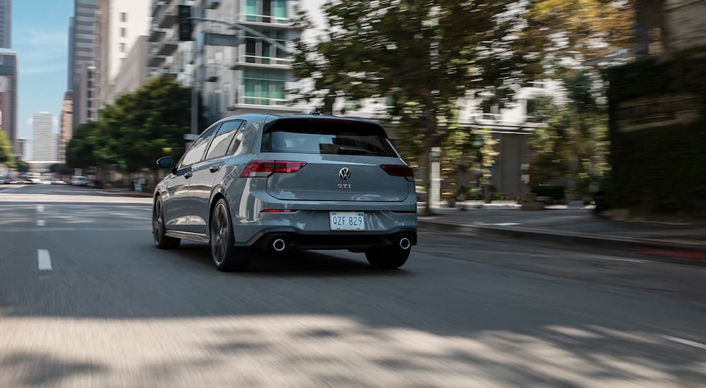 A grey 2022 Volkswagen GTI Autobahn is shown from the rear driving on a city street.