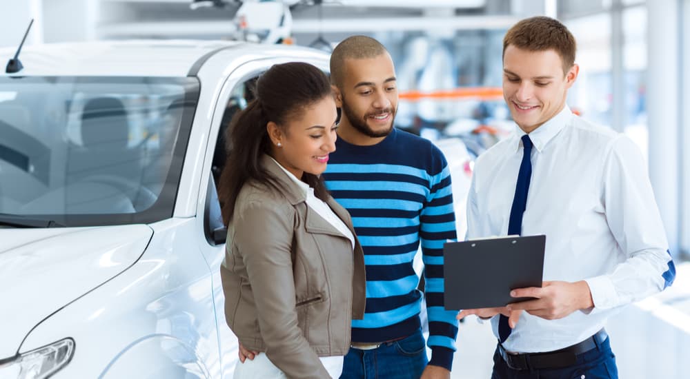 A salesman is shown speaking to customers about valuing their car.