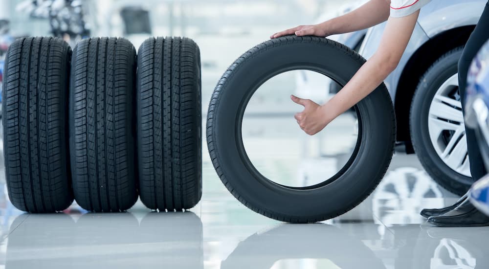 A person is shown giving a thumbs up as they wheel a tire out.