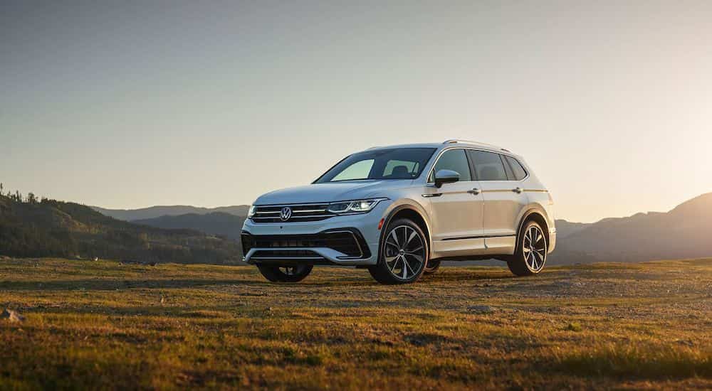 A white 2022 Volkswagen Tiguan is shown from the front at an angle in a field during a 2022 Volkswagen Tiguan vs 2022 Toyota RAV4 comparison.