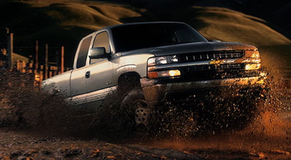 A silver 1999 Chevy Silverado 1500 is shown from the front driving in a desert.