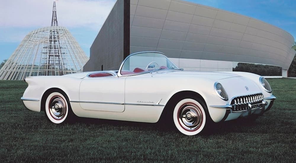 A white 1953 Chevy Corvette is shown parked in an empty field.