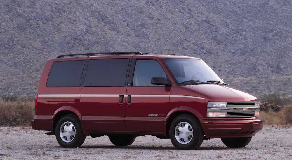 A red 1998 Chevy Astro Van is shown near a used Chevy dealer.