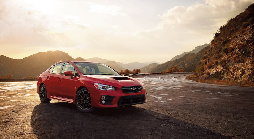 A red 2018 Subaru WRX is shown from the front at an angle while parked on a mountain road after leaving a Subaru used car dealership.