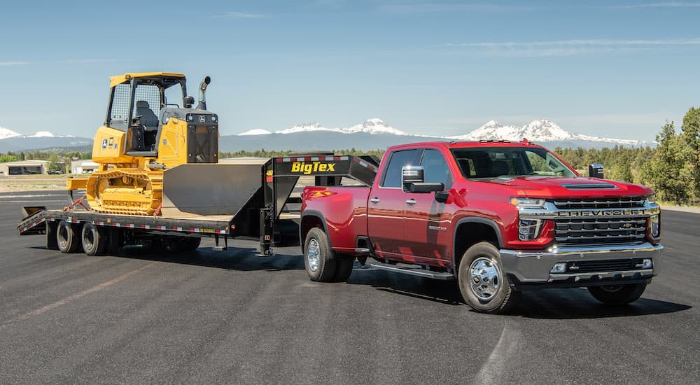 A red 2020 Chevy Silverado 3500HD is shown from the front at an angle while towing a bulldozer.