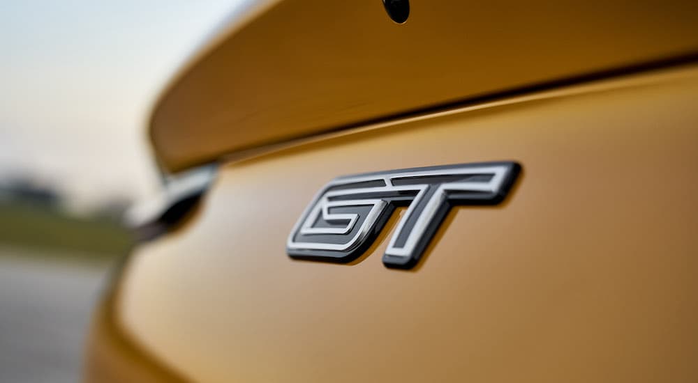 The badge of a yellow 2022 Ford Mustang Mach E GT is shown in close up.