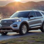 A silver 2022 Ford Explorer Limited is shown driving past a mountain range.