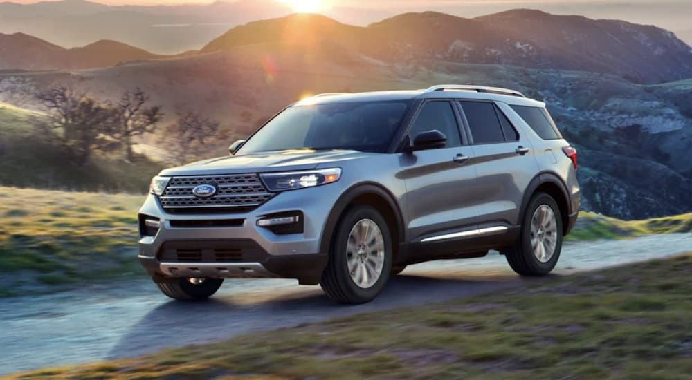 A silver 2022 Ford Explorer Limited is shown driving past a mountain range.