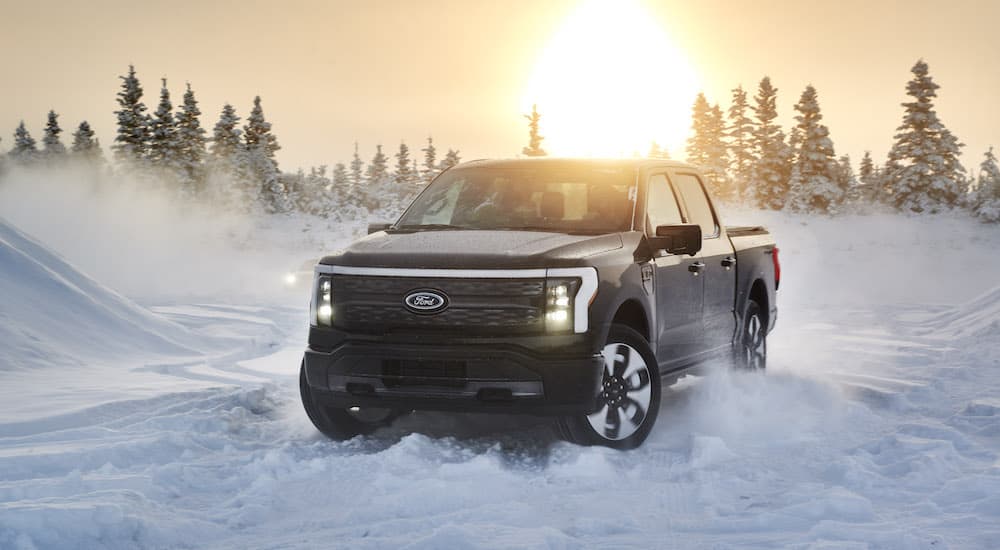 A black 2022 Ford Lightning is shown from the front while driving through snow.