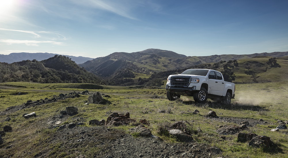 A whit e2022 GMC Canyon AT4 is shown from the front at an angle while driving off-road.