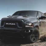 A grey and black 2022 Ram 1500 Classic is shown off-roading on a dirt lot.