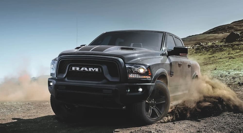 A grey and black 2022 Ram 1500 Classic is shown off-roading on a dirt lot.