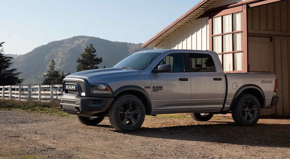 A silver 2022 Ram 1500 Classic Warlock is shown parked outside of a barn.