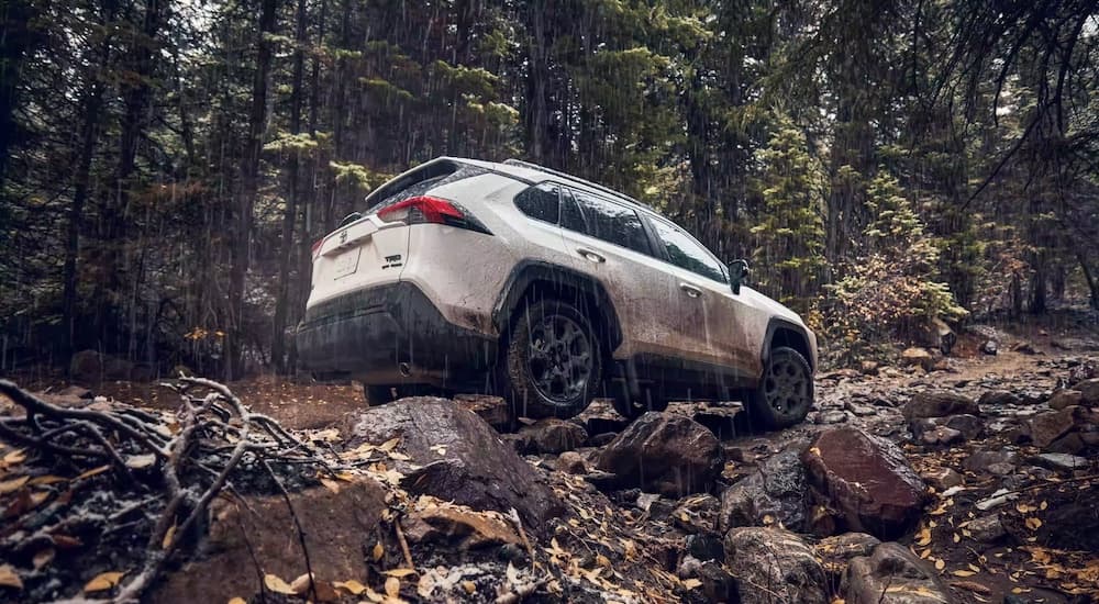 A white 2022 Toyota RAV4 TRD is shown from the rear while driving over rough terrain.