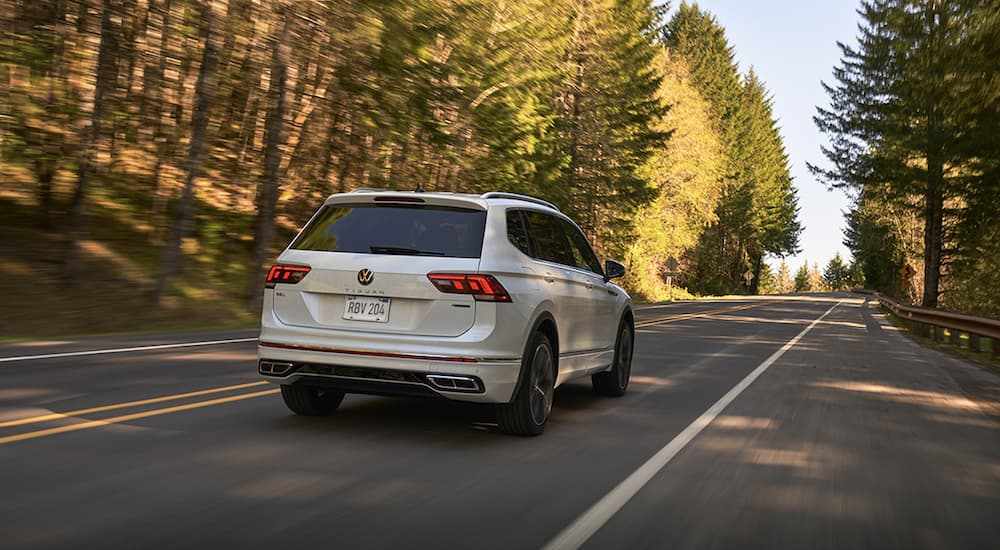 A white 2022 Volkswagen Tiguan is shown from the rear driving on an open road during a 2022 Volkswagen Tiguan vs 2022 Kia Sportage comparison.