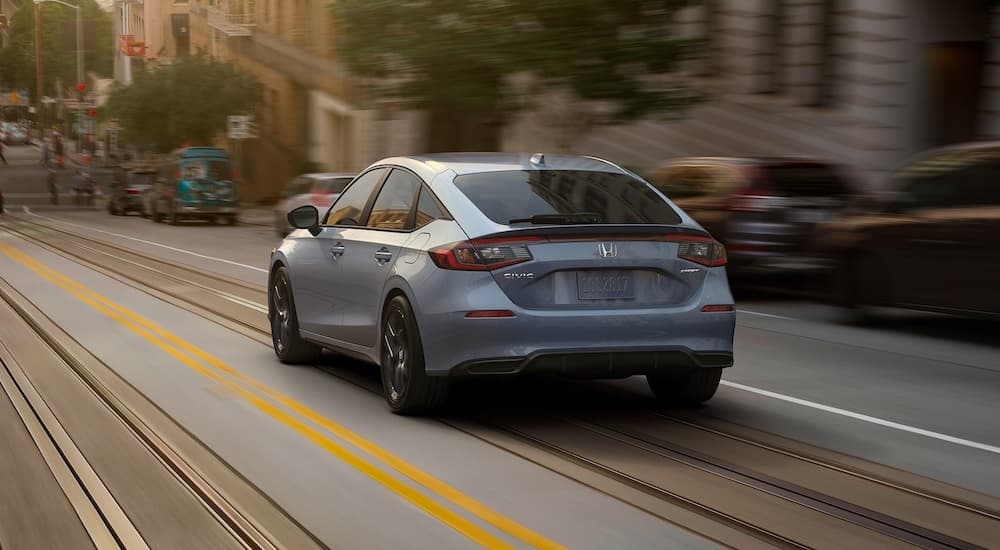 A grey 2022 Honda Civic Sport Hatch is shown from the rear after leaving a dealer that advertises that it has a Honda Civic for sale.