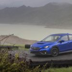 A blue 2022 Subaru WRX is shown from the front while parked on a coastal road.