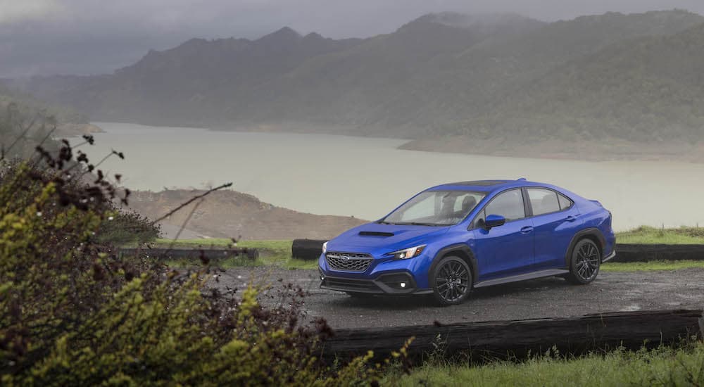 A blue 2022 Subaru WRX is shown from the front while parked on a coastal road.