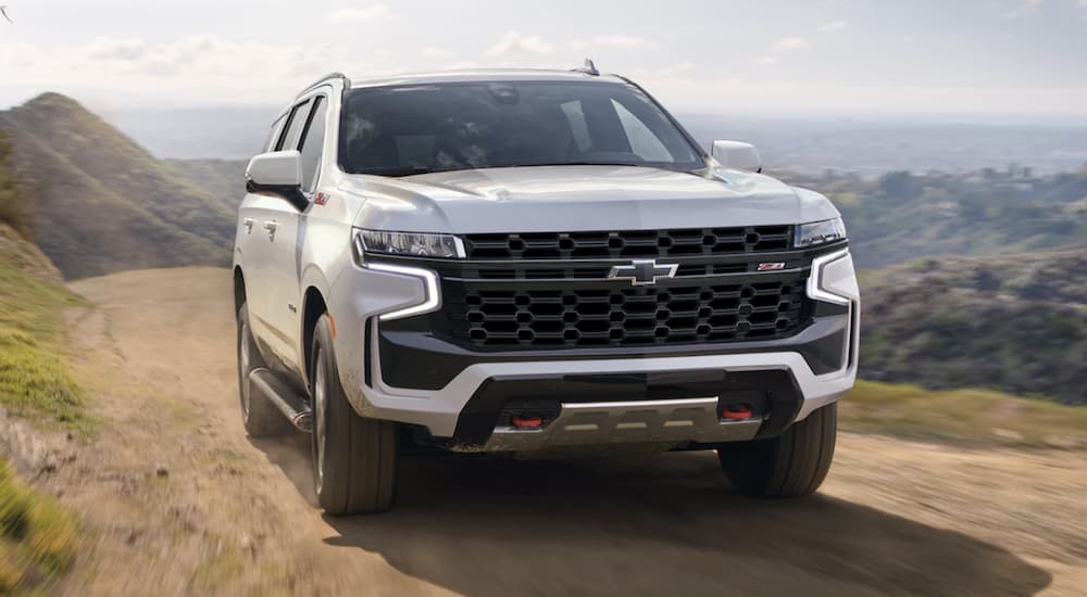 A white 2023 Chevy Tahoe Z71 is shown from the front driving on a dirt road.
