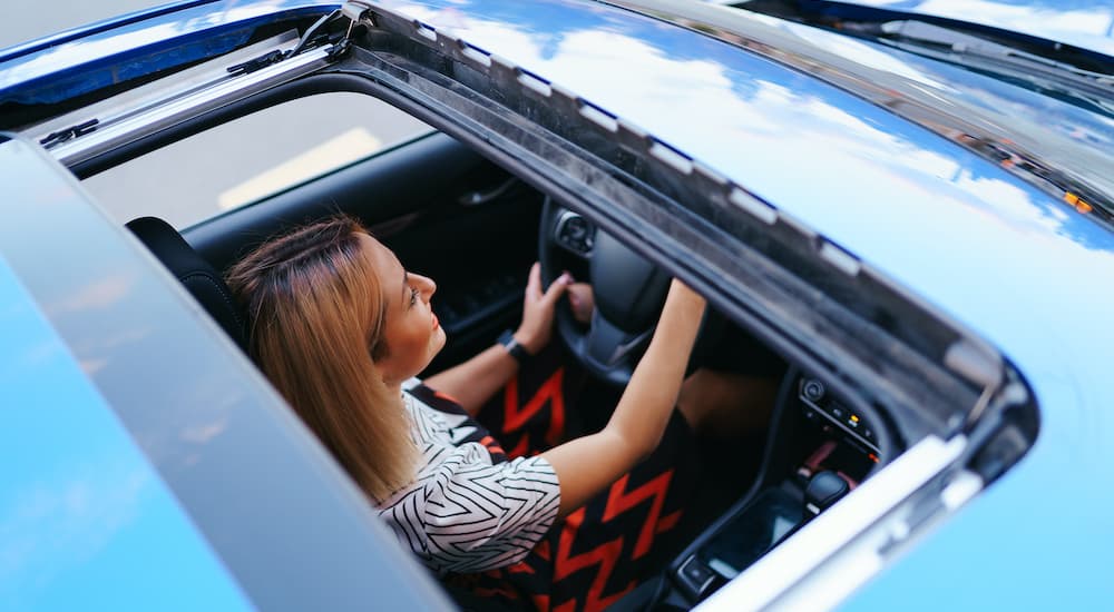 A person is shown driving with an open sunroof.