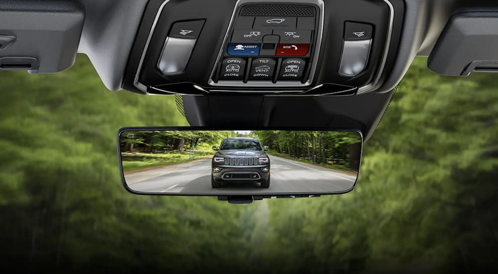 The close up of a rear view mirror shows the 2023 Jeep Grand Cherokee three-row.