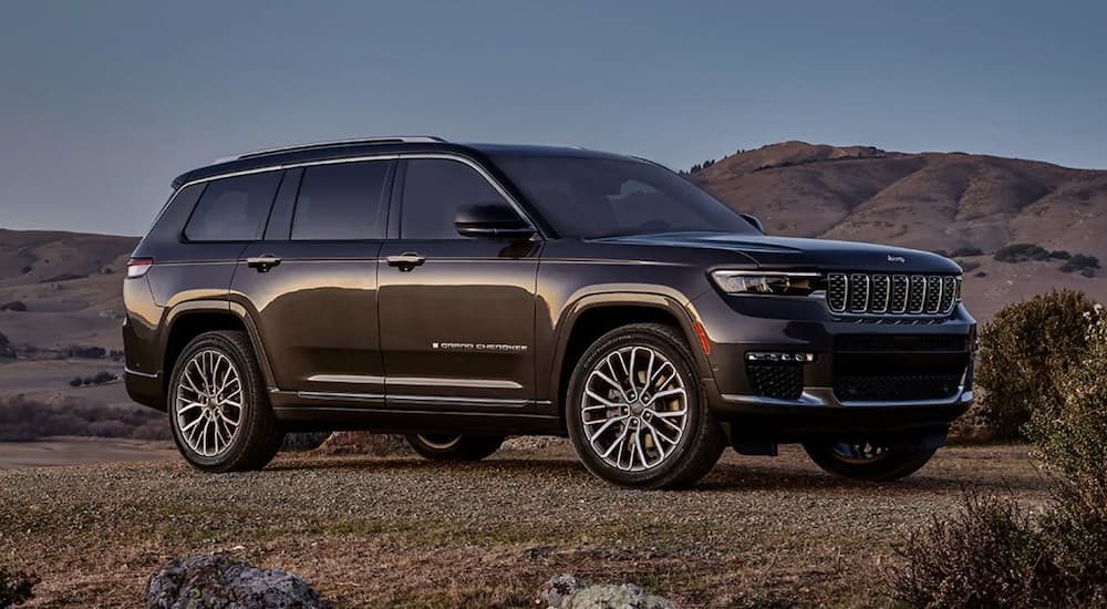 A grey 2023 Jeep Grand Cherokee three-row is shown from the side parked in a desert.