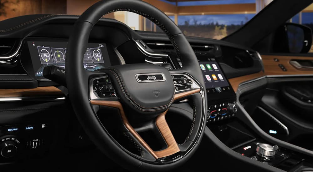 The black interior of a 2023 Jeep Grand Cherokee three-row shows the steering wheel.