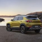 A yellow 2023 Chevy Trailblazer Activ is shown from the rear at an angle on a lakeshore.