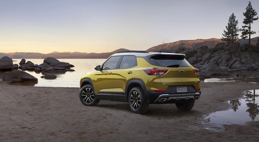 A yellow 2023 Chevy Trailblazer Activ is shown from the rear at an angle on a lakeshore.