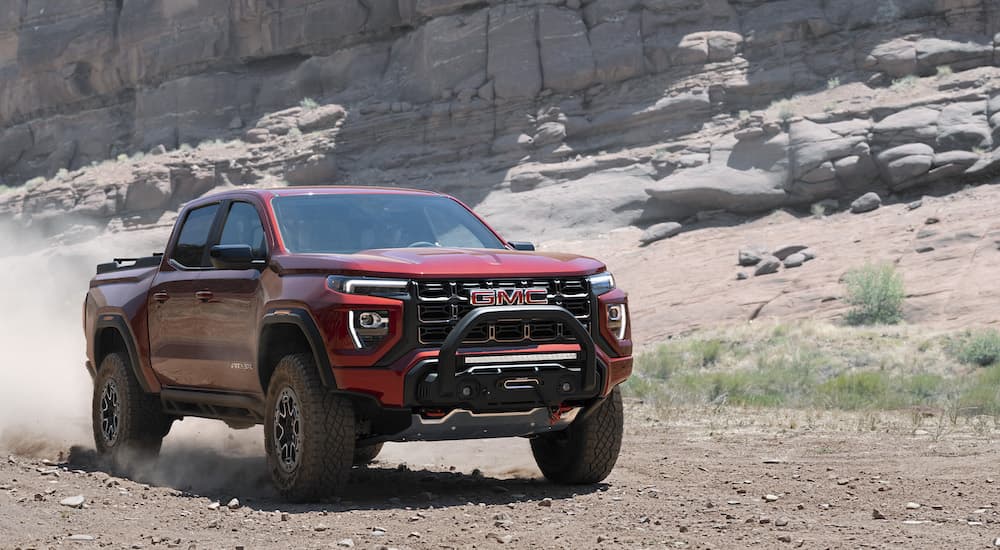 A red 2023 GMC Canyon AT4x is shown from the front at an angle while driving though the desert.