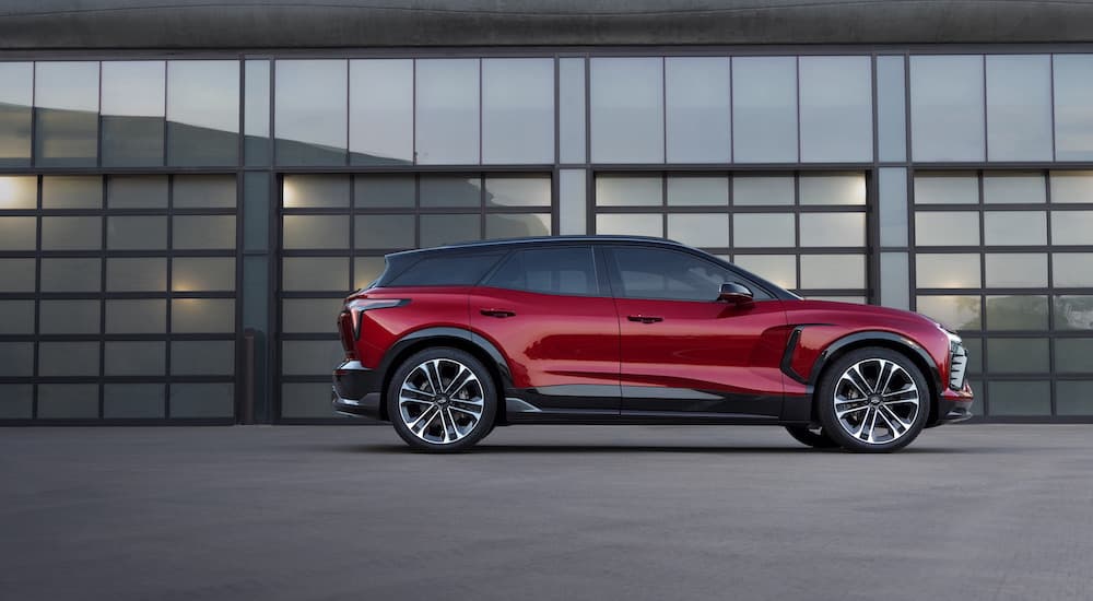 A red 2024 Chevy Blazer EV is shown from the side while parked in front of garage doors.