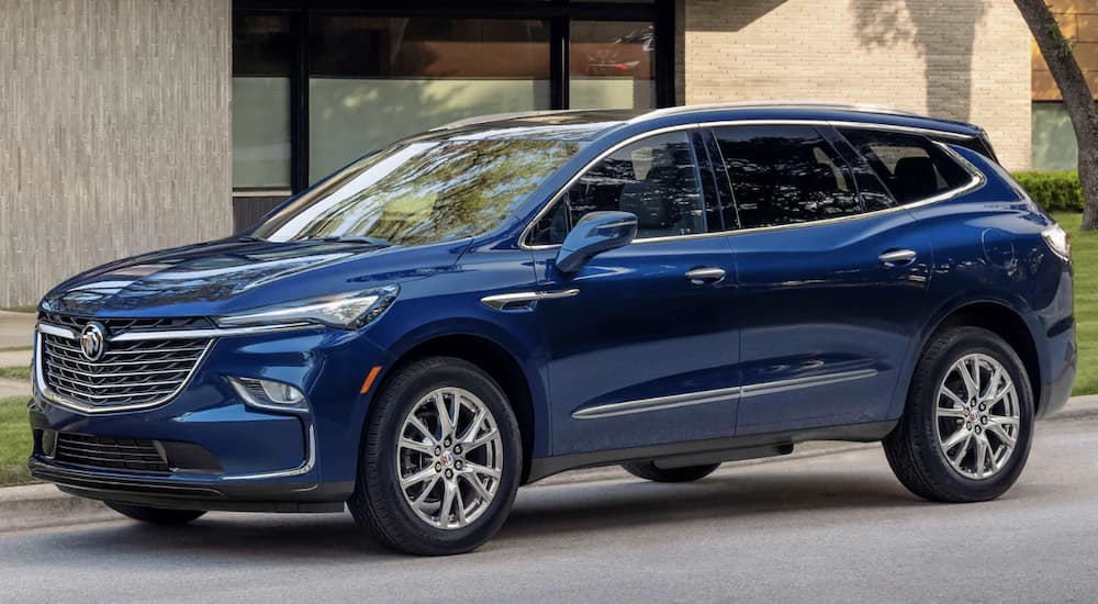 A blue 2023 Buick Enclave is shown from the side parked in front of a building after leaving a Buick Enclave dealer.