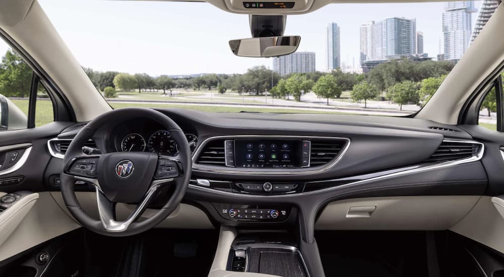 The black interior of a 2023 Buick Enclave shows the steering wheel and infotainment screen.