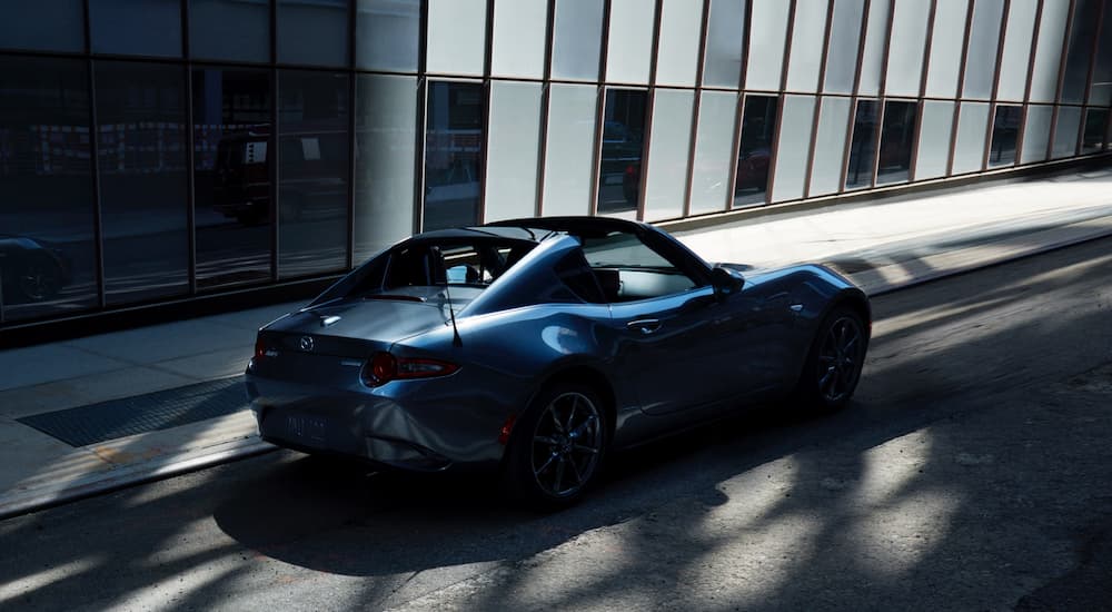 A dark blue 2022 Mazda MX-5 Miata is shown on a city street after leaving one of the areas leading car dealerships.