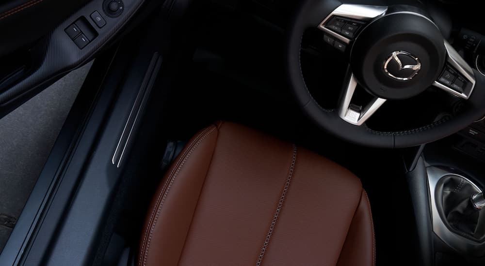 The brown leather seat and black steering wheel is shown in a 2022 Mazda MX-5 Miata.