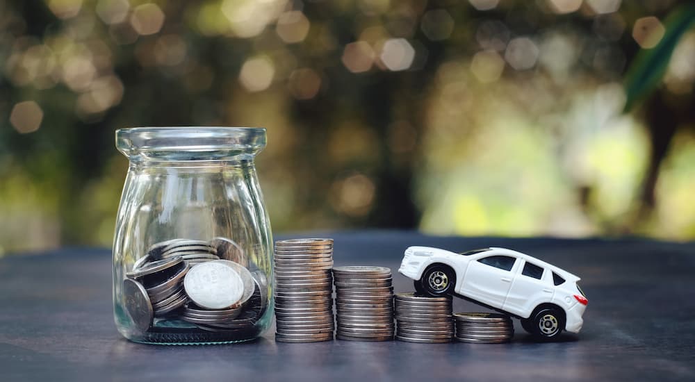 A toy car is shown driving up stacks of coins.